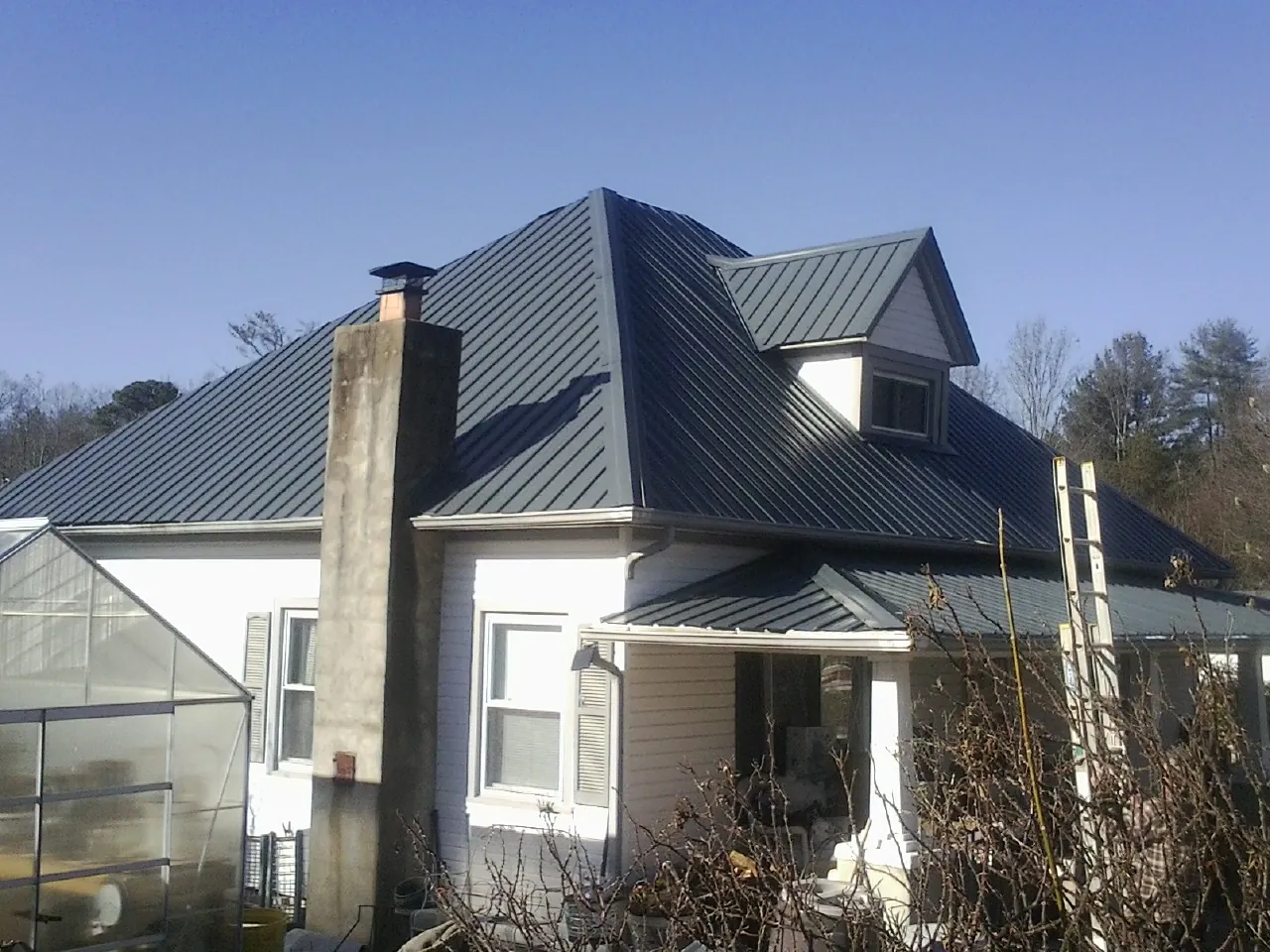 Dark blue standing seam metal roof on a white farmhouse with dormer — Slate & Tile Roof Repair by Roofing Brothers in Prescott Valley