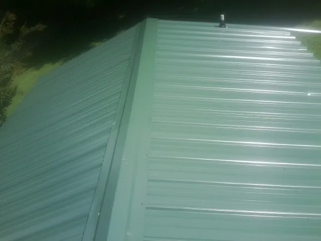 New green metal panels meeting at the ridge of a roof — Flat Roof Repair work by our crew in Prescott Valley