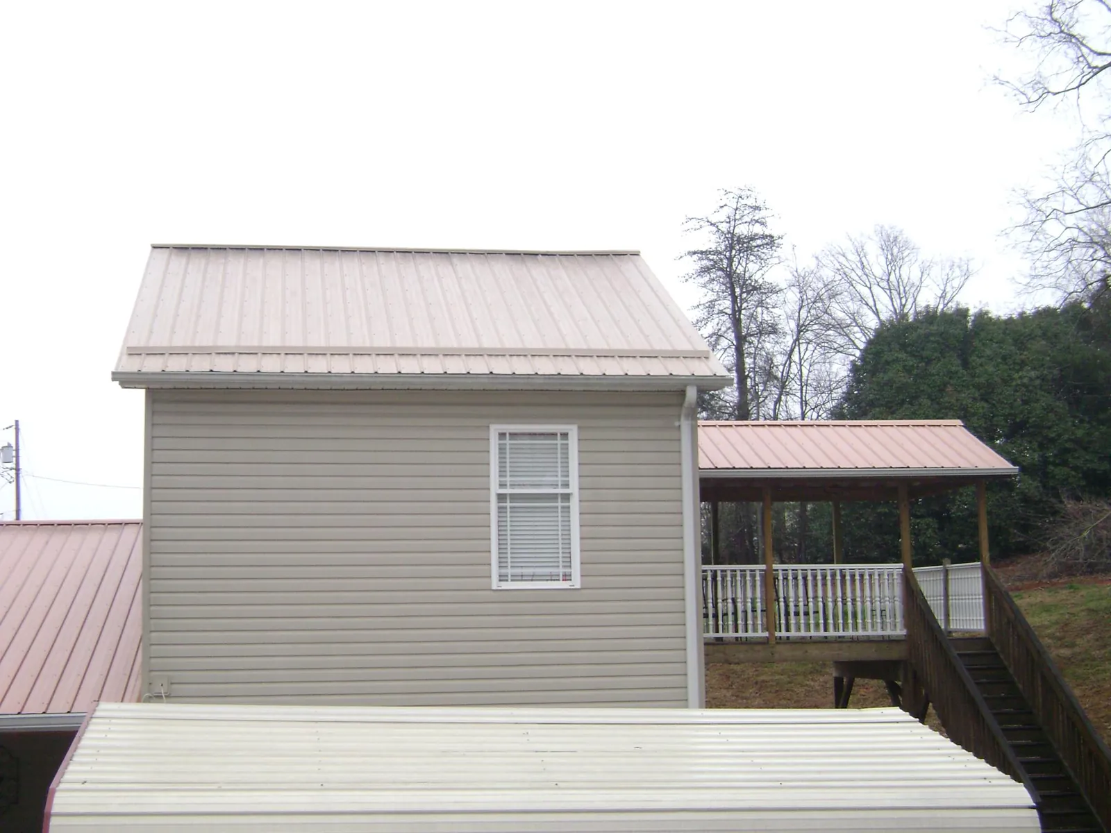 Tan metal roofs on a two story addition and attached porch, from a Roof Replacement job in Prescott Valley
