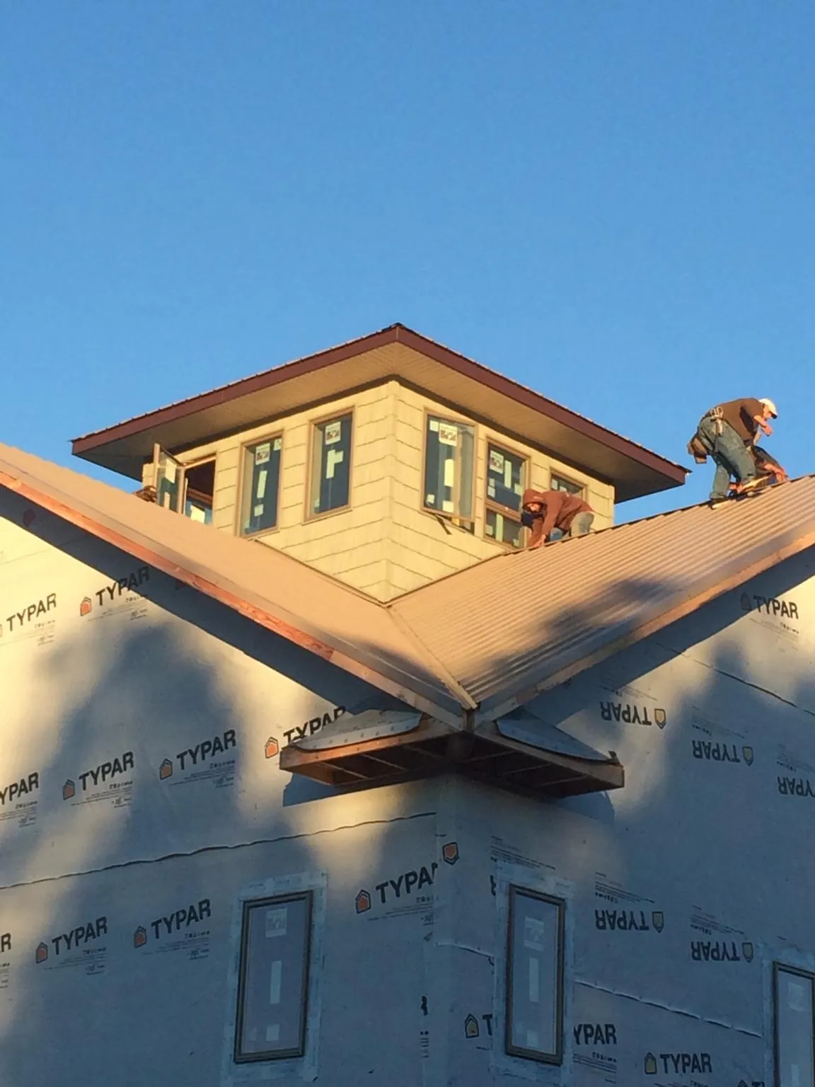 Roofers working around a rooftop cupola on a new metal roof at sunset — Roof Waterproofing in Prescott Valley by Roofing Brothers